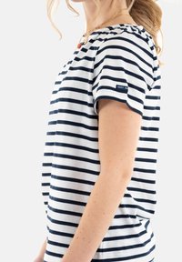 Camiseta de rayas blanca y azul marino con mangas cortas, cuello redondo y una pequeña etiqueta en la manga. Fabricada en suave tela de algodón.