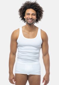 Hvid bomulds tanktop med rund halsudskæring og ærmeløs design, parret med hvide undertøjsbukser; glat tekstur og tætsiddende form.
