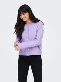 Lavendelfarget ullcardigan med rund hals, knappestolpe foran og lange ermer. Myk tekstur, litt kort modell. Sorte bukser vist.