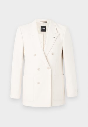 Double-breasted blazer in off-white fabric, featuring two front pockets, four buttons, notch lapels, and a small logo pin on the chest.