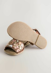 Sandali marroni con ricami floreali, dotati di una ampia fascia in tessuto, fibbia regolabile e suola in gomma testurizzata. Decorati con dettagli in filo rosa e oro.