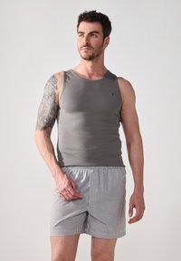 Grå ærmeløs tanktop med ribbet tekstur, parret med lysegrå stribede shorts med en elastisk talje.
