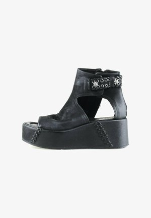 Sandale à plateforme noire en cuir avec bout ouvert, côtés découpés, bride de cheville ornée d'œillets et de clous argentés, et semelle épaisse cousue.