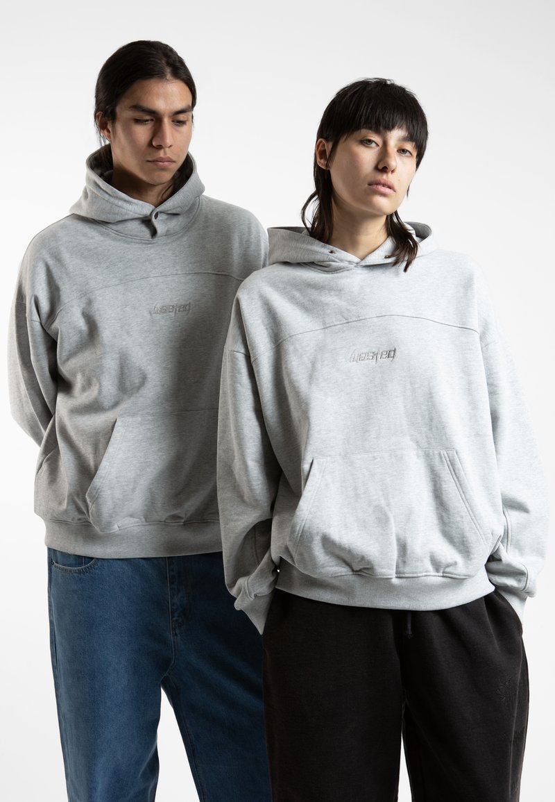 Sweatshirts gris avec poches kangourou, poignets côtelés et un logo brodé subtil. Associés à un jean et à un pantalon noir. Matériau doux en polaire.