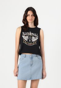 Juodas be rankovių trumpas viršus su „Rock and Roll“ grafika, derinamas su šviesiai mėlyna džinsine mini sijonu. Minkšta medžiaga, laisvas kirpimas ir priekiniai kišenės.