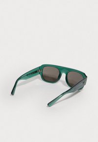 Óculos de sol verdes translúcidos com lentes castanhas, armações retangulares e hastes elegantes com acentos de marca discretos.
