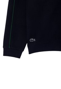 Marineblaues Strick-Sweatshirt mit strukturiertem Rippmuster, grünem Seitenstreifen und einem weißen gestickten Logo nahe dem Saum.