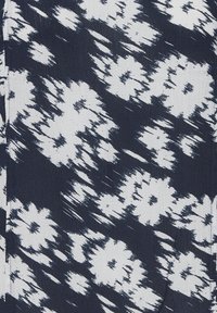 Tissu bleu marine avec un motif floral blanc, présentant une surface texturée. Les motifs apparaissent flous avec des formes et tailles variées, créant un effet de mouvement.