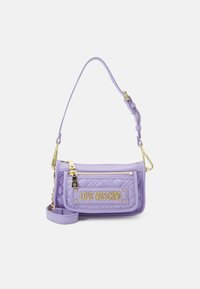 Fialová prošívaná kabelka se zlatým kováním, s přední kapsou na zip a odnímatelným ramenním popruhem. Na přední straně je vyražené logo.