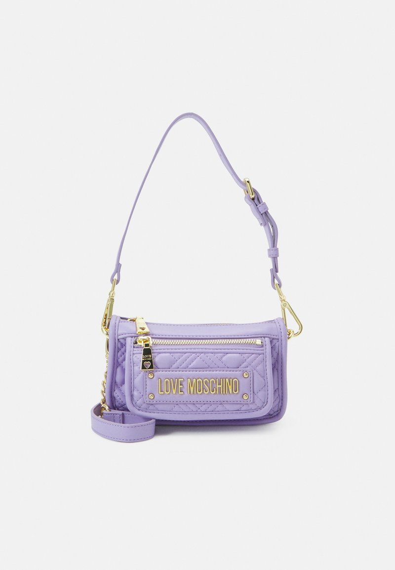 Fialová prošívaná kabelka se zlatým kováním, s přední kapsou na zip a odnímatelným ramenním popruhem. Na přední straně je vyražené logo.