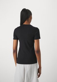 T-shirt noir à manches courtes, design ajusté avec un col rond. Tissu lisse et léger. Vue de l'arrière, montrant une construction simple.