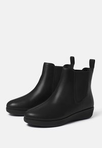 Schwarze Leder-Angelschuhe mit elastischen Seiteneinsätzen und Schlaufen. Rundspitze und niedrige Keilsohle bieten Komfort und Stabilität.