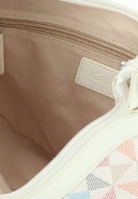 Witte stoffen tas met een geometrisch patroon in pastelkleuren, met een beige interieur, een ritsvak en een merklabel aan de binnenkant.