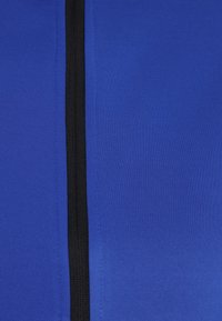 Tessuto atletico blu con una superficie liscia, caratterizzato da una cerniera nera verticale lungo il centro.