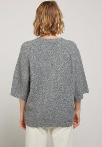 Pull en laine gris surdimensionné avec des manches courtes, un col rond et une finition texturée. Tissu doux et confortable avec un fit décontracté.
