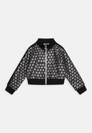 Chaqueta negra con cremallera completa, con un patrón de logotipos circulares blancos "MK" por todo el tejido, y puños, cuello y dobladillo acanalados.