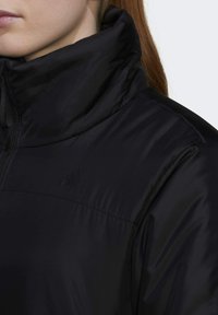 Zwarte zip-up jas met hoge kraag, gemaakt van gestructureerde nylon stof, met een klein, ton-sur-ton logo op de borst.