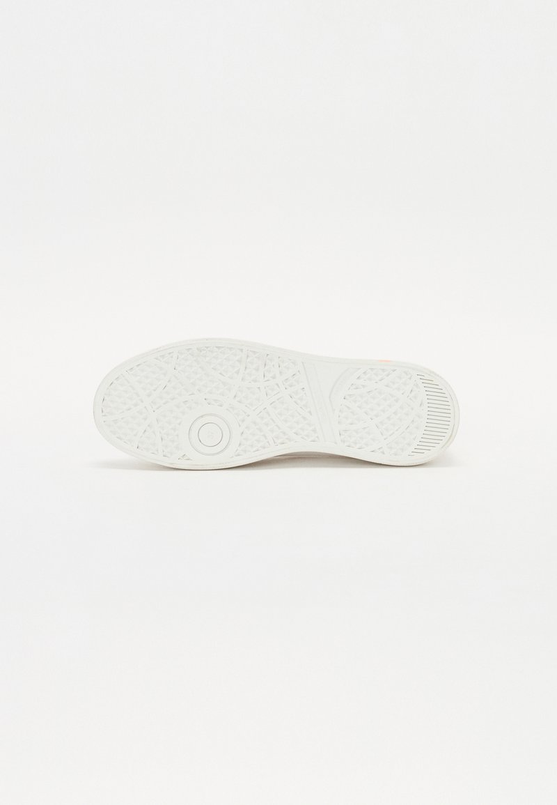 Semelle de sneaker blanche avec un motif texturé, des points de traction circulaires et un bord lisse. Présente un logo embossé sur le côté.