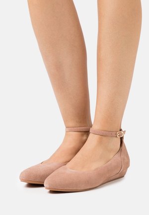 Bailarinas de ante rosa con punta afilada, correa al tobillo y pequeño tacón de cuña. Textura suave y diseño minimalista con un cierre seguro.