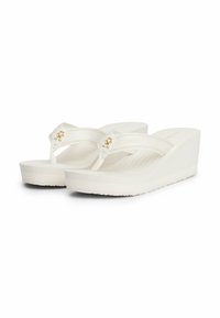Witte wedge flip-flops met een textuur op de rubberen zolen, stoffen banden met gouden accenten en subtiele branding op de voetbed.