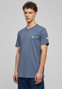 Short-sleeve, blue cotton t-shirt with a round neck, featuring a small logo on the chest and white lettering on the sleeve.
