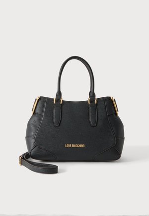 Sac à main Moschino noir avec deux poignées, boucles dorées sur les côtés et bandoulière détachable sur fond blanc.
