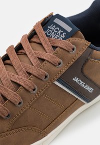 Bruine leren sneaker met een gestructureerd oppervlak, bruine veters, een blauwe tong en een witte streep met het "JACK & JONES" logo.