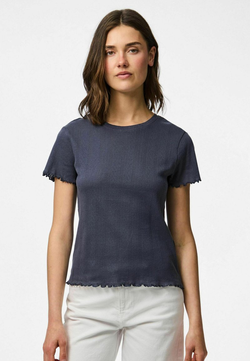 Marinblå t-shirt med kort ärm, tillverkad av texturerat tyg med ribbat mönster och vågiga kanter vid ärmarna och nederkanten.