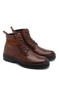 Brązowe skórzane botki za kostkę z wiązaniem z przodu, kontrastującymi akcentami z zamszu, fakturowanym wykończeniem i grubymi czarnymi gumowymi podeszwami.