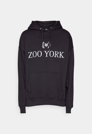 Hoodie noir avec une poche kangourou, capuche à cordon de serrage et texte "ZOO YORK" en blanc avec un logo au-dessus. Fabriqué en tissu doux et texturé.