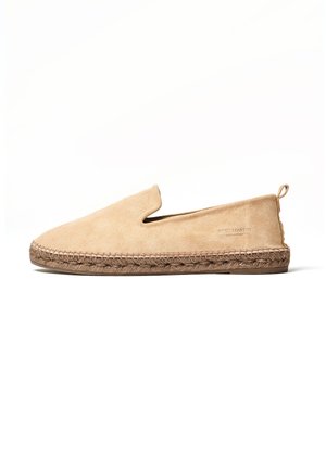 Tan suede slip-on shoe with a rounded toe and elastic slit. Features a braided jute midsole and a small heel pull tab.