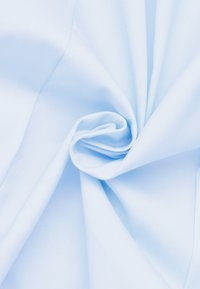 Light blue fabric with a smooth texture, intricately folded to form a spiral shape, highlighting its softness and lightweight quality.