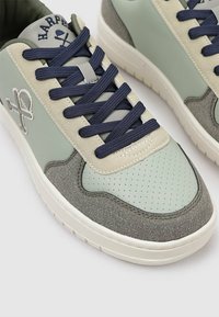 Zapatilla con parte superior de cuero verde menta, detalles en ante gris y cordones azul marino. Cuenta con una caja de toe perforada y un detalle de logo bordado.