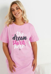 Rosa bomullsklänning med korta ärmar och rund halsringning. Trycket innehåller "drömmen börjar här" i blandade färger och små hjärtan.