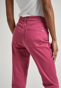 Rosa bomullbyxor med en figurnära midja och två bakfickor. Diskret sömnadsdetalj på fickorna och en slät textur.