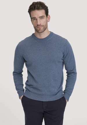 Blauer Strickpullover mit rundem Halsausschnitt, gerippten Bündchen und Saum. Das Material wirkt weich mit einer subtilen Textur und wird mit dunklen Hosen getragen.