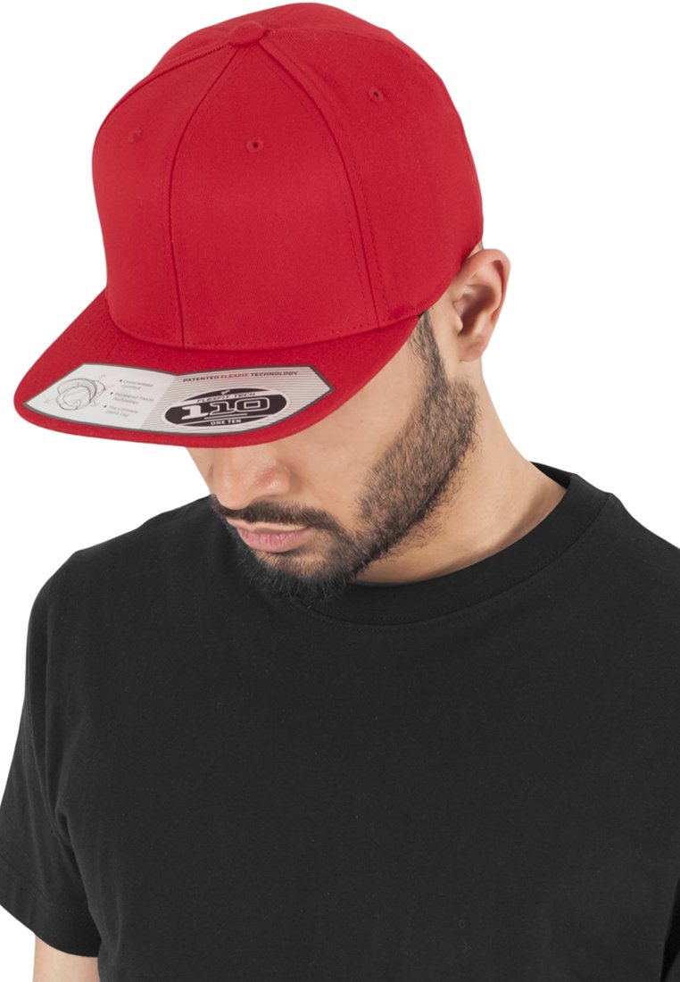 Gorra de béisbol roja con visera plana, fabricada en tela. Presenta orificios de ventilación y una etiqueta interna con marca, combinada con una camiseta negra.