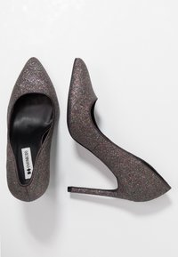 Des chaussures à talons aiguilles scintillantes dans des teintes sombres, avec un bout pointu et une découpe sur le côté. Elles présentent une surface lisse et texturée ainsi qu'un talon stiletto fin.