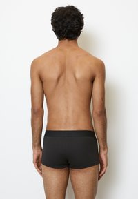 Svart bomullsboxerunderkläder med ett mjukt elastiskt midjeband, vy från baksidan, som visar en slät textur och en åtsittande design.