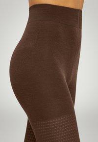 Brune strækleggings med høj talje, der har et struktureret gittermønster i den nederste del og en glat, blød stoffinish.