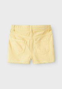 Shorts de mezclilla amarillos con dobladillo deshilachado, dos bolsillos traseros con un diseño curvado y una textura suave. Vista trasera mostrada.