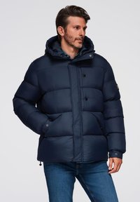Granatowa kurtka puchowa z kapturem, wyposażona w zamek błyskawiczny i zapinanie na napy, boczne kieszenie oraz pikowany design dla zapewnienia ciepła.