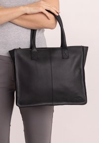 Borsa a spalla nera in pelle con doppi manici, texture liscia, forma rettangolare e dettagli cuciti. Chiusura con zip lungo il bordo superiore.