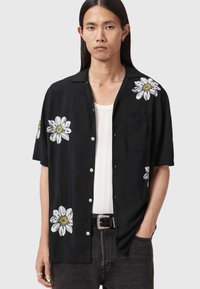 Czarna koszula z krótkim rękawem z białą kwiatową haftowaną dekoracją. Posiada zapięcie na guziki z przodu oraz naszywaną kieszeń. Wykonana z lekkiego materiału.