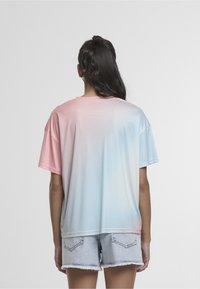 Tričko s krátkým rukávem v přechodu barev z růžové do světle modré. Vyrobeno z hladké, lehké látky. Kombinováno s lehkými džínovými šortkami.