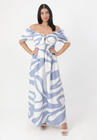 Abito maxi bianco e azzurro chiaro con motivi ondulati; design scollato sulle spalle, dettaglio a nodo sul davanti e vita arricciata.