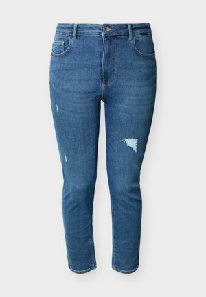 Jean denim bleu coupe ajustée avec une légère usure sur la cuisse et la jambe gauche, doté de poches avant et d'une fermeture à bouton.