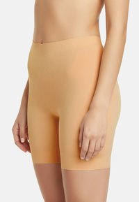 Nude árnyalatú, sima, könnyű anyagból készült alakformáló rövidnadrág, magas derekú és varrás nélküli kialakítással, amely kifinomult vonalvezetést biztosít.