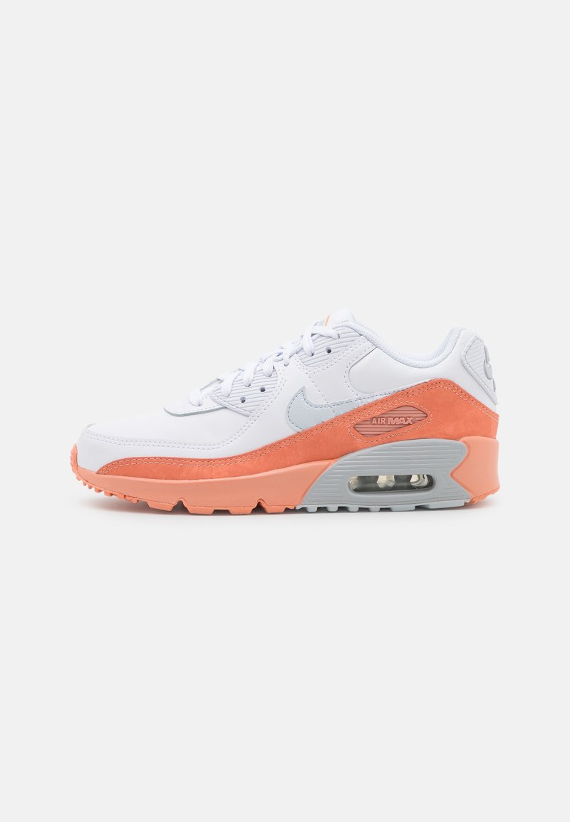 Tenisky Nike Air Max 90 mají bílou koženou svršek s oranžovými semišovými akcenty, šedou podrážku a viditelnou Air jednotku v patě.