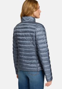 Veste matelassée grise avec un col montant et un design matelassé horizontal. Elle présente des poignets élastiques et une texture lisse et brillante.